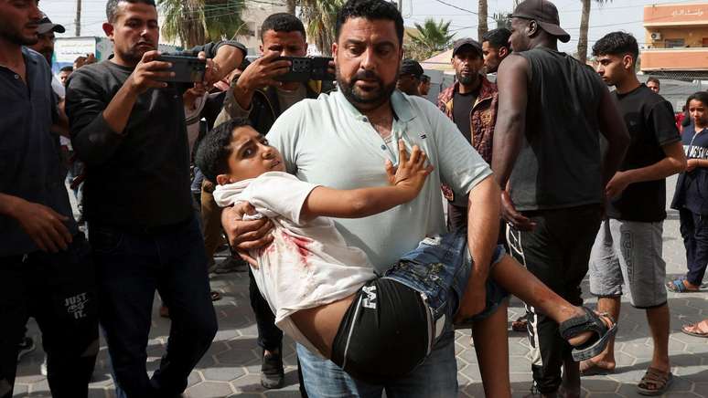 Homem carrega criança ferida até hospital na Faixa de Gaza após novo ataque de Israel