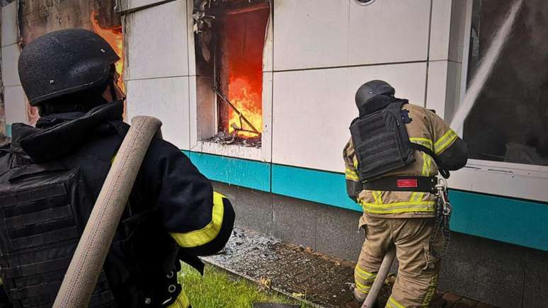 Esta foto tirada e divulgada pelos serviços de emergência ucranianos em 18 de maio de 2025 mostra equipes de resgate apagando um incêndio em um prédio após ataques de drones na região de Kiev.